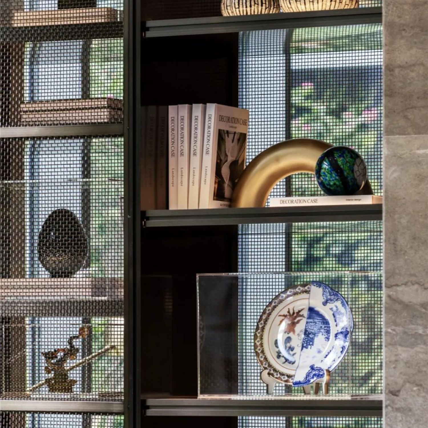 Decorative Objects displayed on shelves, featuring books, a green vase, and a decorative plate.