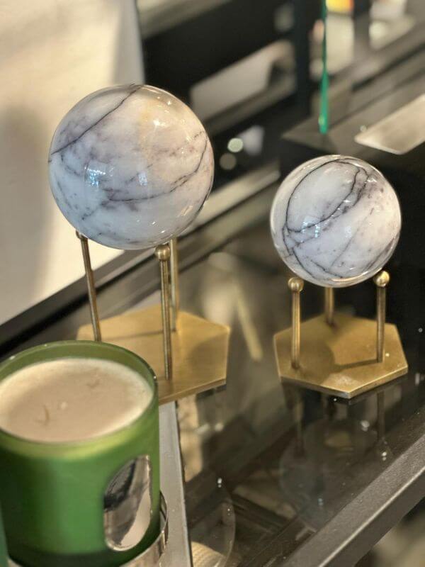 White marble decorative sphere with lilac veins on hexagonal brass stands.