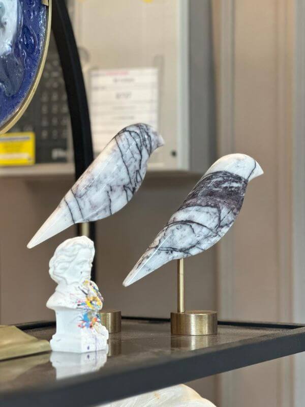 White marble bird decorative object with grey veins on brass stand, adding elegance to home decor.