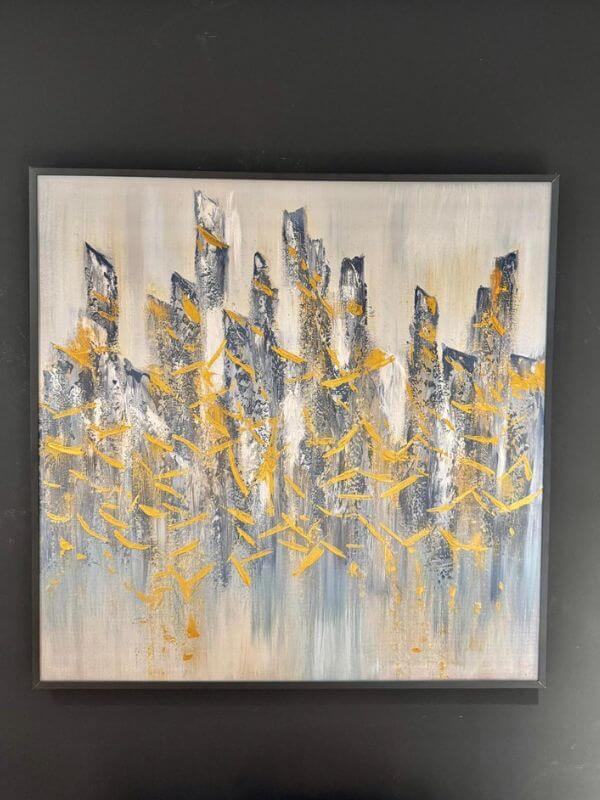 Abstract oil painting with black metal frame showcasing a modern city skyline in gold and blue hues.