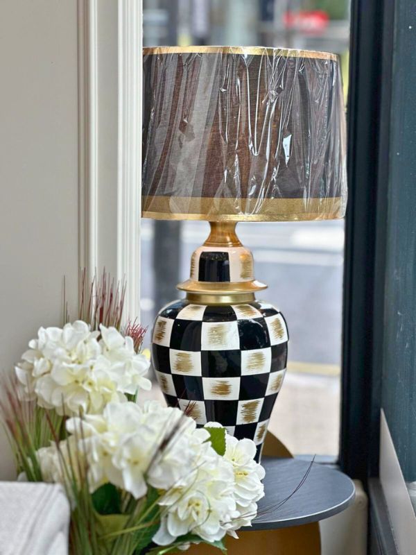 Black and gold checkered ceramic table lamp with lamp shade and floral decor.