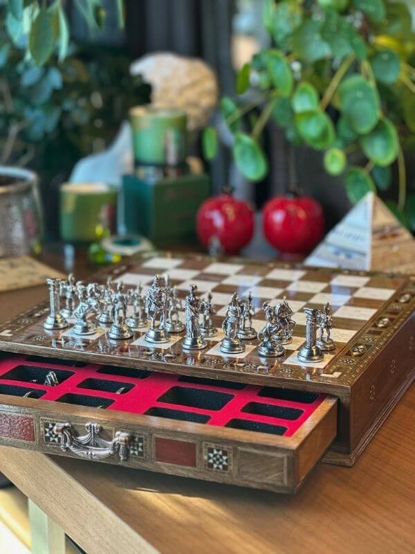 Large handmade chess set with intricately designed metal pieces and an elegant wooden board.