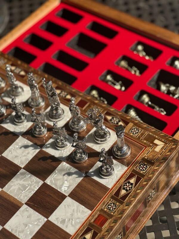 Large handmade chess set with intricately designed metal pieces and an elegant wooden board.