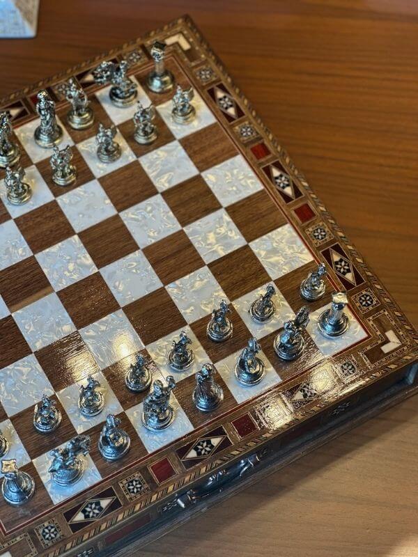 Large handmade chess set with intricately designed metal pieces and an elegant wooden board.