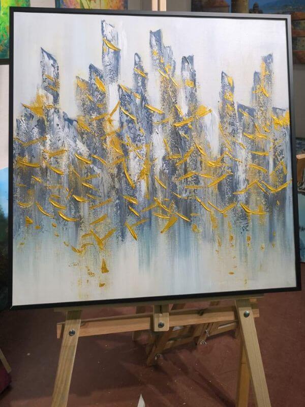 Abstract oil painting with black metal frame featuring a modern city skyline in gold and blue tones.