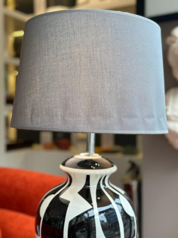 Black and white abstract ceramic table lamp with a gray fabric shade on a stylish decor background.