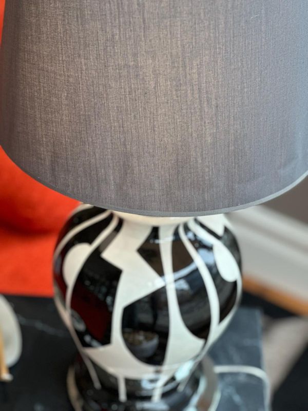 Black and white abstract ceramic table lamp with a grey lampshade, showcasing modern artistic design.