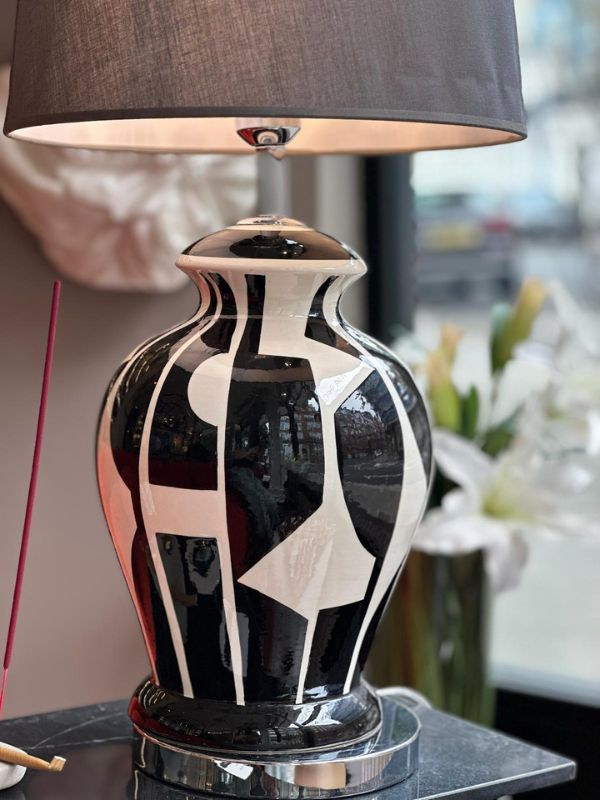 Black and white abstract ceramic table lamp with artistic design and fabric shade.