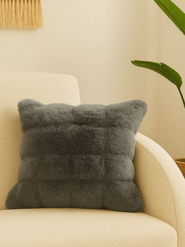 Anthracite faux fur pillow case on a cream couch, showcasing its plush texture and modern elegance.