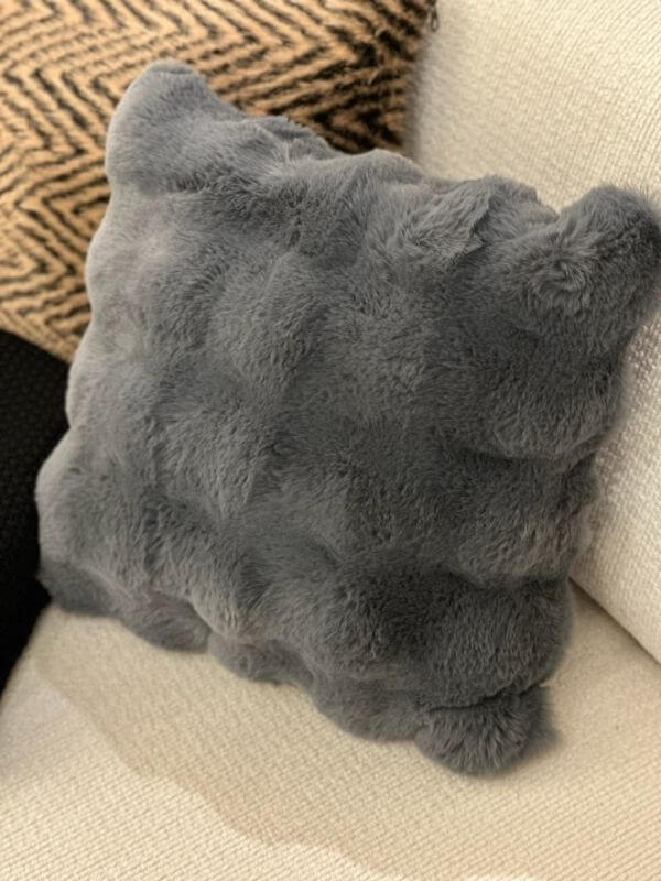 Anthracite faux fur pillow case on a textured sofa, showcasing a plush and luxurious feel.