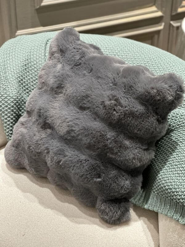 Anthracite faux fur pillow case resting on a knitted blanket, showcasing its plush texture and modern design.