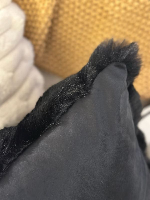 Close-up of a black faux fur throw pillow cover showcasing its plush texture and luxurious design.