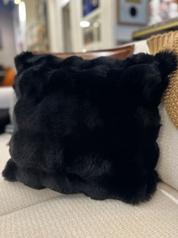 Black faux fur throw pillow cover on a sofa, adding luxury and sophistication to home décor.