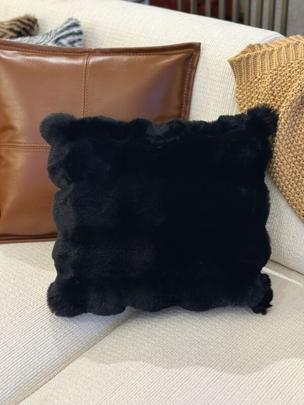 Black faux fur throw pillow cover on a light-colored sofa, showcasing plush texture and elegant design.