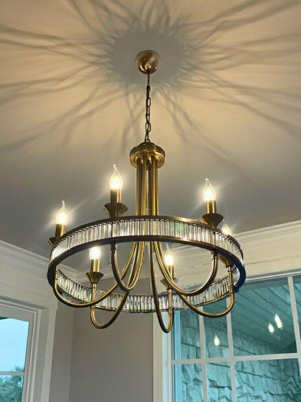 Modern round crystal chandelier with a sleek gold finish and glowing bulbs, illuminating a stylish interior.
