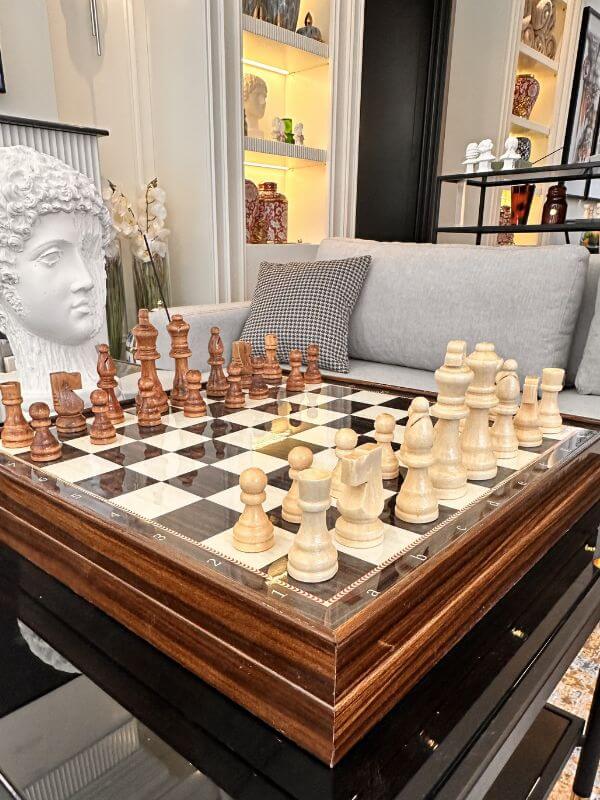 Large classic chess set displayed elegantly in a stylish living room with intricate wooden pieces.