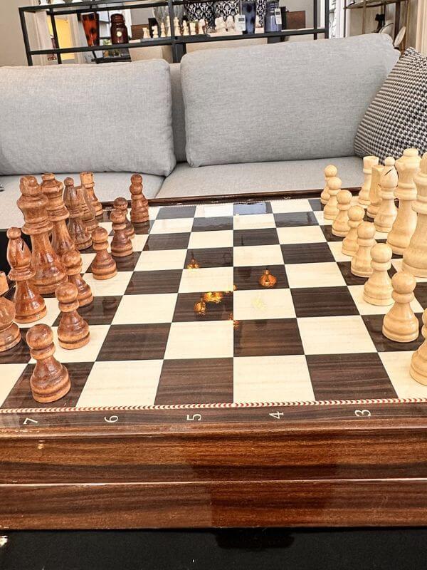 large classic chess set displayed on a stylish table with a modern sofa in the background.