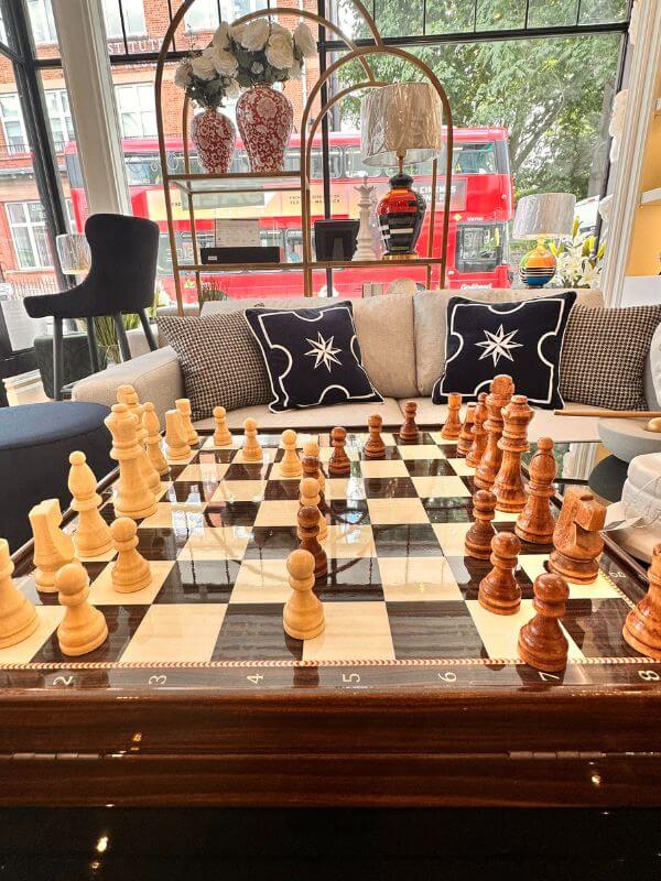 Large classic chess set displayed on an elegant table in a stylish living area, showcasing intricate pieces.