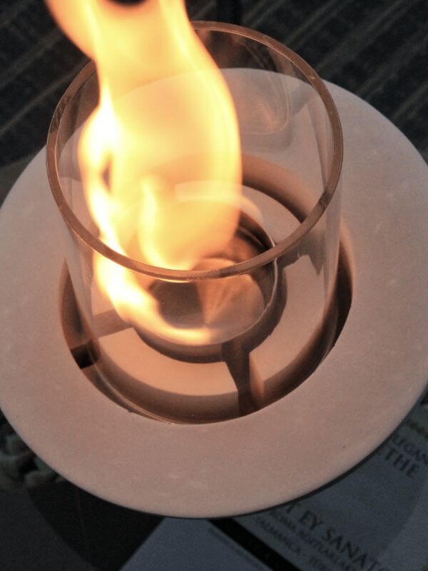 Close-up of a flame in a decorative glass concrete fireplace, showcasing its elegant design and functionality.