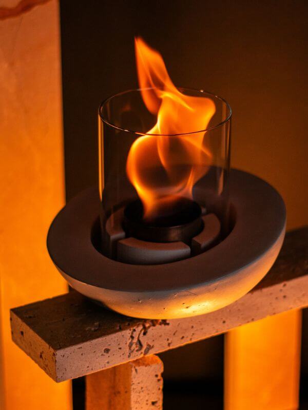 Decorative glass concrete fireplace with a flame, designed for modern interiors and elegance.