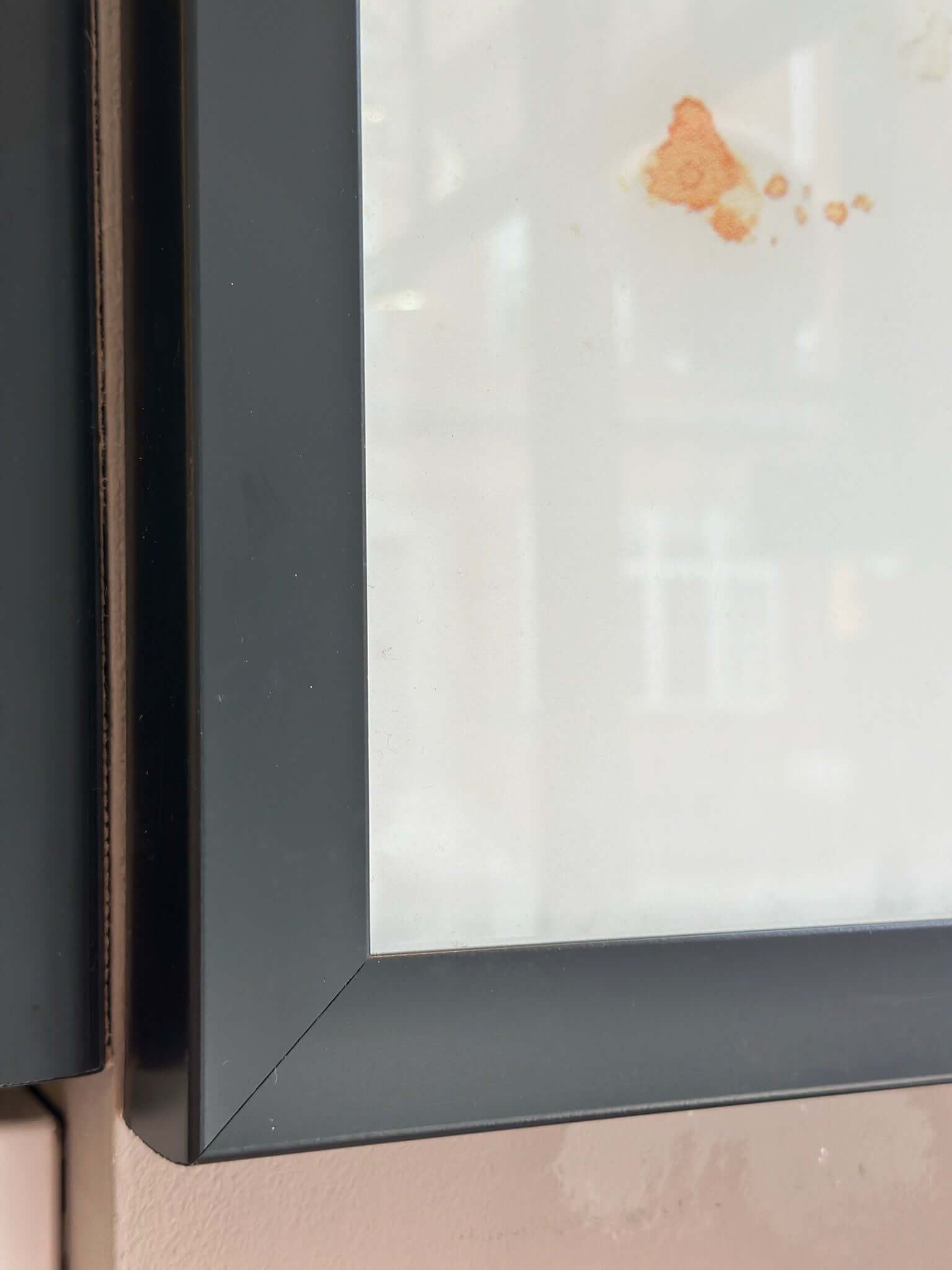 Close-up of framed glass wall art black metal frame showcasing sleek design and corner detail.