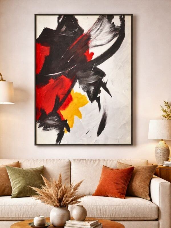 Abstract canvas art with black metal frame showcasing vibrant red, deep black, and bright yellow tones in a modern living room.