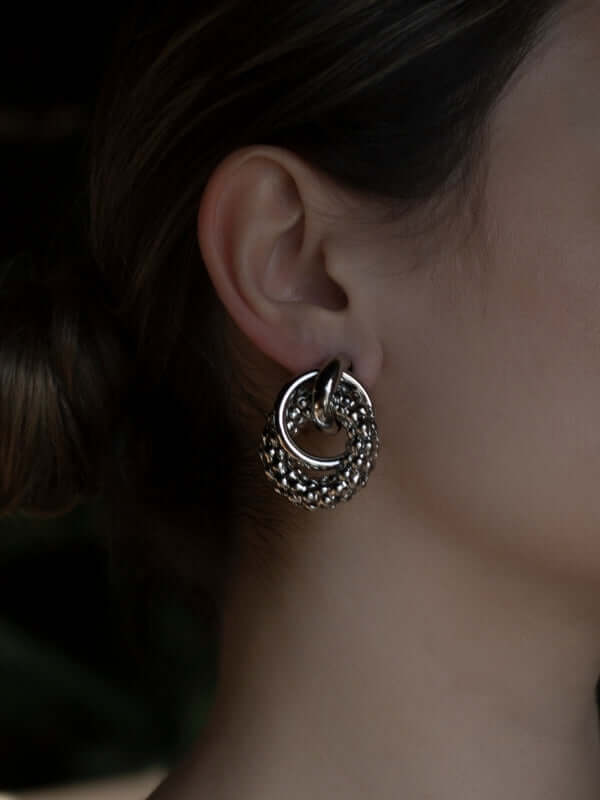 Model wearing sculptural link earrings showcasing artistic design and modern elegance.
