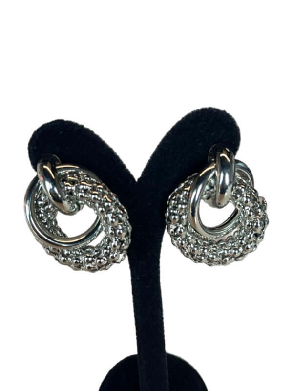 Sculptural link earrings displayed on a black stand, showcasing their unique design and sophisticated style.