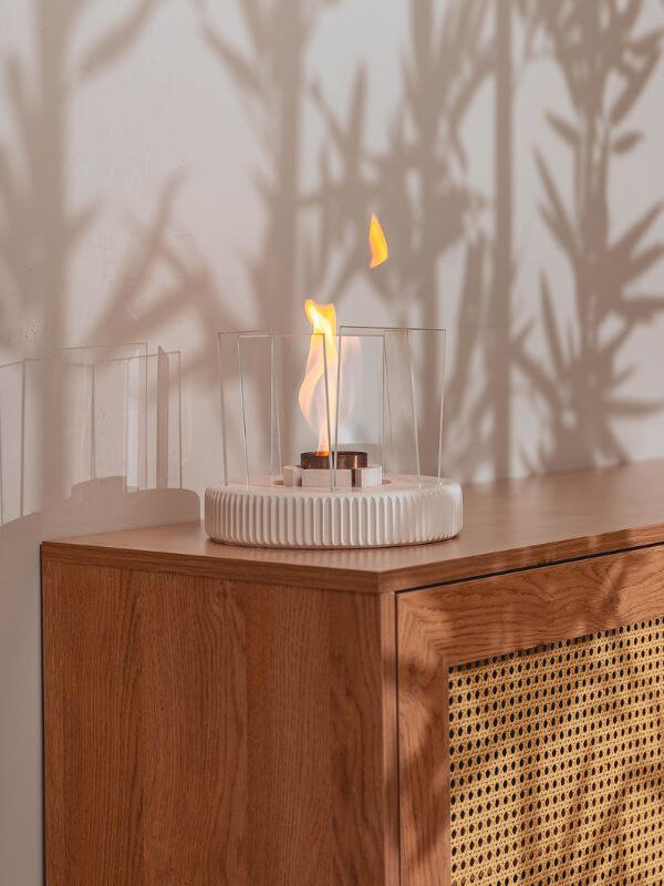 Modern concrete fireplace accent with flame in a stylish living space setting on a wooden surface.