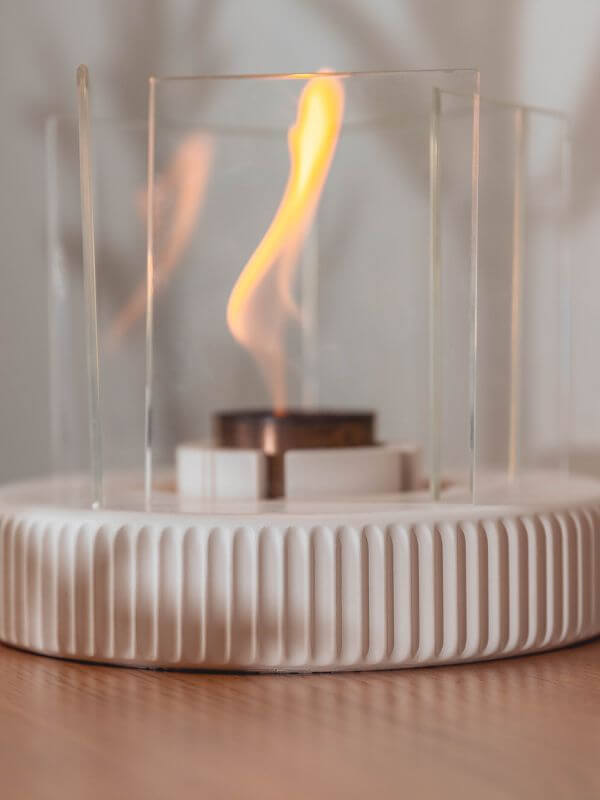 Modern concrete fireplace accent featuring a sleek design with flame encased in glass for contemporary living spaces.