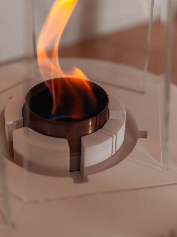Modern concrete fireplace accent with flame rising from the decorative centerpiece, showcasing warmth and elegance.