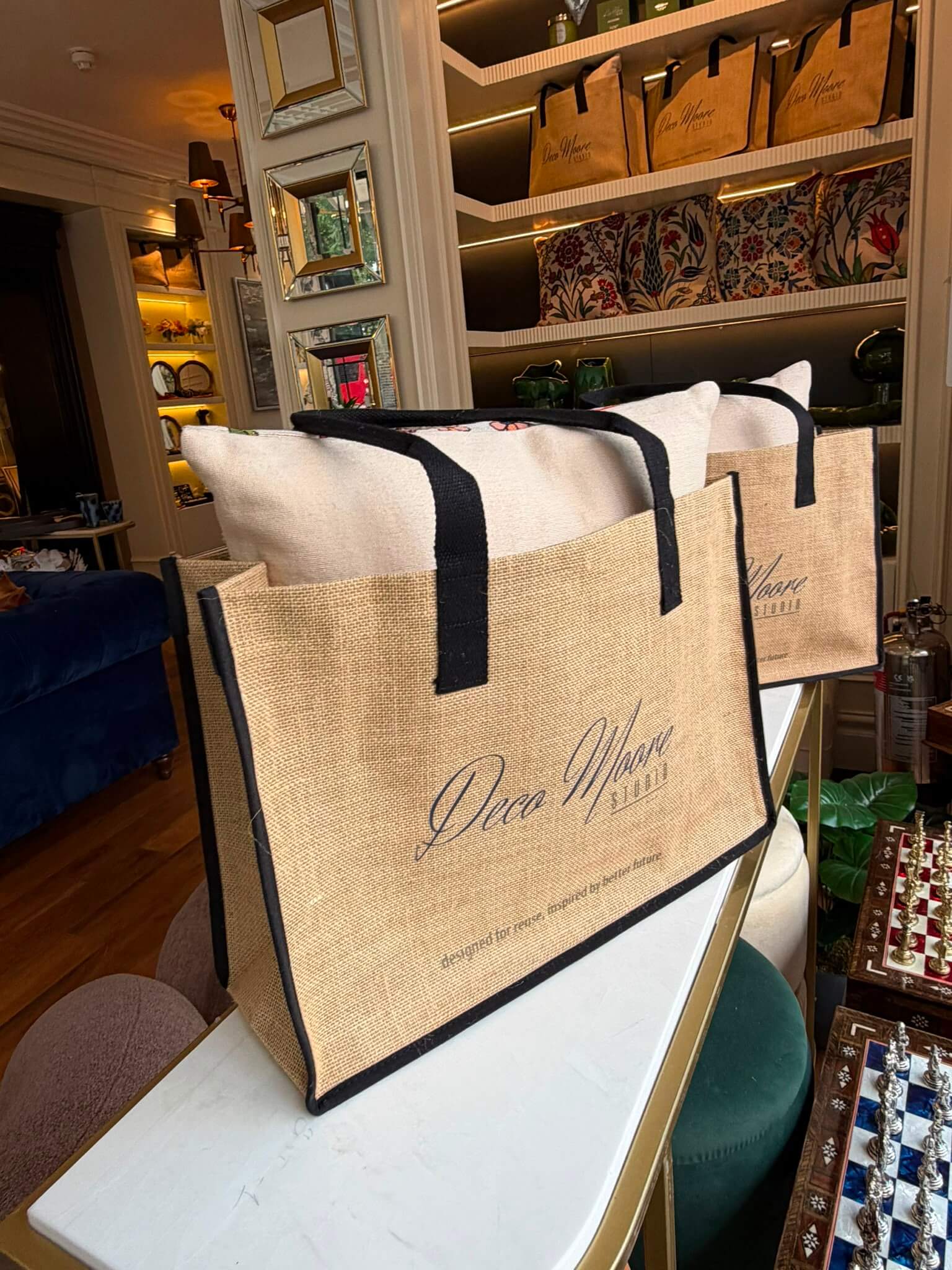 Deco Moore Jute Tote Bag in natural jute texture with black trims and handles, ideal for shopping and everyday use.