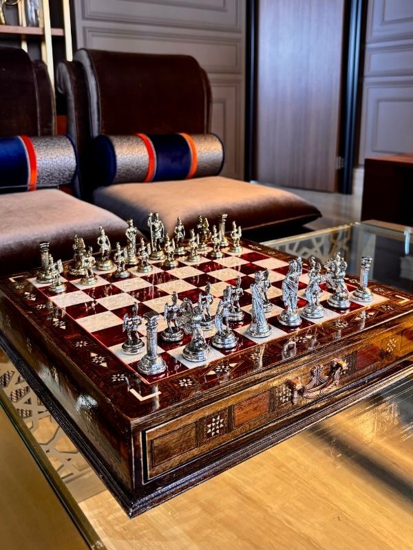 Large handmade chess set displayed elegantly on a polished table, showcasing intricate metal chess pieces.