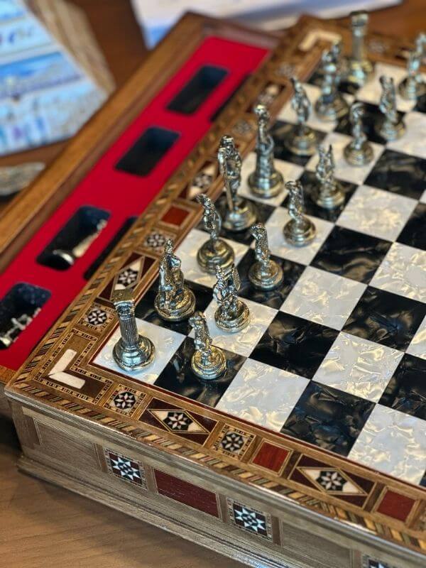 Large handmade chess set with intricately designed metal pieces and a beautifully finished wooden board.